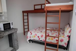 1 dormitorio con litera y microondas en Flats Nascer do Sol, en Cayru