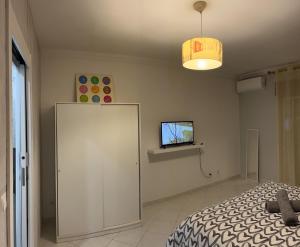 sypialnia z łóżkiem i telewizorem na ścianie w obiekcie OCEAN VIEW Quartos w Faro