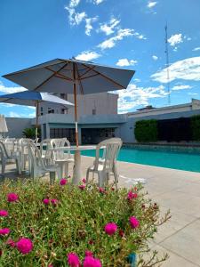 伊瓜蘇的住宿－伊瓜蘇夫茲酒店，一组椅子和一把遮阳伞,位于游泳池旁
