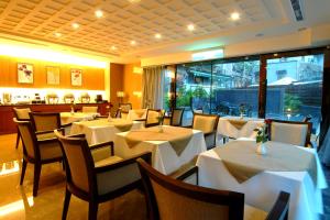 a dining room with white tables and chairs in a restaurant at Jingan Classic Inn in Zhonghe
