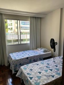 a hotel room with two beds and a window at FAROL DA BARRA 2/QUARTOS in Salvador