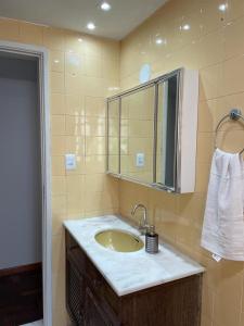 a bathroom with a sink and a mirror at FAROL DA BARRA 2/QUARTOS in Salvador