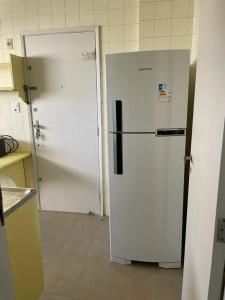 - un réfrigérateur blanc installé dans une cuisine à côté d'une porte dans l'établissement FAROL DA BARRA 2/QUARTOS, à Salvador