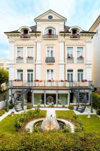 ein Gebäude mit einem Brunnen davor in der Unterkunft Hotel Villa am Kurpark in Bad Homburg vor der Höhe