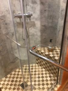 a shower with a glass door and a checkered floor at La Nesliere Chambres d'Hôtes Bio in Saint-Symphorien-des-Monts