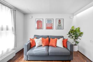 sala de estar con sofá gris y almohadas de color naranja en Best Location LUX Home, 2 Blocks to Sbwy, Sleeps 9, en Sapporo