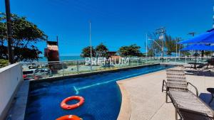 a swimming pool with two chairs and a red life preserver at Studio TOP pra homeoffice, internet voando in Macaé