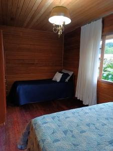 een slaapkamer met een blauw bed en een raam bij Recanto Flora in Rancho Queimado