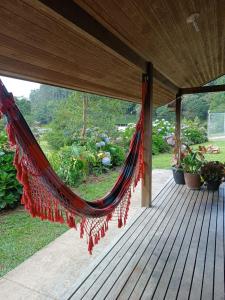 een hangmat hangend op een veranda met een tuin bij Recanto Flora in Rancho Queimado