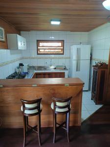 een keuken met 2 stoelen aan een aanrecht en een koelkast bij Recanto Flora in Rancho Queimado