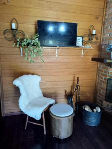 een kamer met een stoel en een tv aan de muur bij Recanto Flora in Rancho Queimado