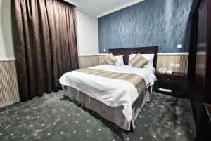 ein Hotelzimmer mit einem großen Bett und einer blauen Wand in der Unterkunft قصور الشرق للاجنحة الفندقية Qosor Al Sharq in Dschidda