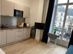 a kitchen with white cabinets and a large window at Studio Opera in Paris