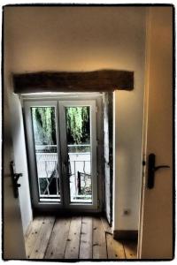 an open door to a room with two windows at Appartements de la ferme du Brocey in Crolles