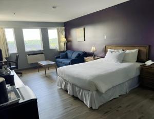 1 dormitorio con 1 cama grande y 1 silla azul en Florenceville Inn, Restaurant & Pool, en Florenceville