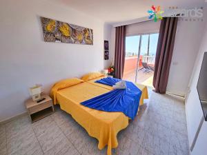 een slaapkamer met een groot bed en een blauwe deken bij 7Lizards - Ocean View Apartments in Puerto de Santiago