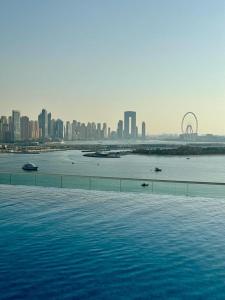 a large swimming pool with a city in the background at Beachside Bliss: Stylish New Studio at Seven Palm in Dubai