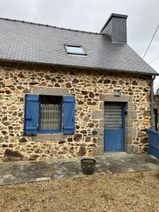 une maison en pierre avec une porte bleue et une fenêtre dans l'établissement Ti Mamm Gozh, à Plouha