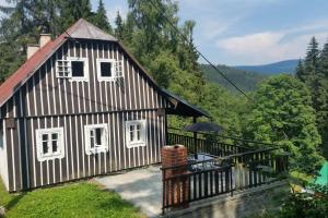 a small black and white house with a balcony at Stylová roubená chalupa Jizerské hory in Kořenov