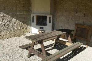 a picnic table in front of a building with an oven at Stylová roubená chalupa Jizerské hory in Kořenov