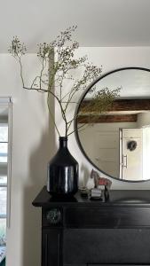 a black vase sitting on a table with a mirror at B&B No. 42 in Valkenburg