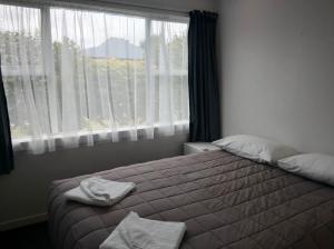 a bedroom with a bed and a large window at Queens Park Motels in Invercargill