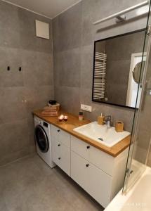 a bathroom with a sink and a washing machine at Comfy, Familly friendly apartment. Balcony. Garage. in Warsaw