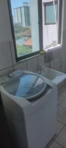 a white toilet in a bathroom with a window at Apartamento da Praia in Navegantes