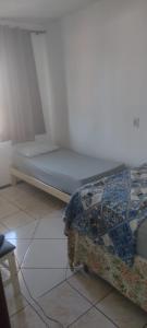 a room with a bed sitting on a tiled floor at Apartamento da Praia in Navegantes