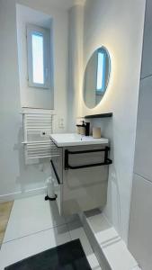 Baño blanco con lavabo y espejo en Appartement rénové proche du parc de la tête d'or en Villeurbanne