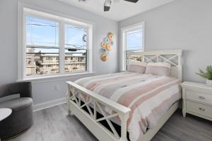 a white bedroom with a bed and two windows at 204 E Primrose Unit 201 in Wildwood