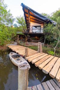 uma casa sobre a água com um barco à sua frente em Recanto Ecológico em São Gabriel