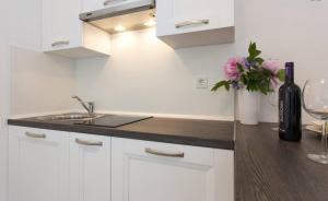 a white kitchen with a sink and a bottle of wine at Studio stonehouse in Ičići