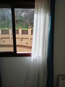 a window with a white curtain and a view at Rincón de María José in Monachil