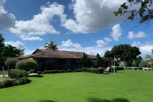 une maison avec une grande pelouse devant elle dans l'établissement Sítio em Aldeia com piscina e vista para o vale, à Camaragibe