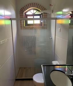 La salle de bains est pourvue d'une douche en verre et de toilettes. dans l'établissement Sítio em Aldeia com piscina e vista para o vale, à Camaragibe