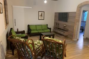 a living room with a green couch and a tv at Sítio em Aldeia com piscina e vista para o vale in Camaragibe