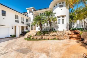 uma grande casa branca com palmeiras e uma entrada em Villa Ahina em Honolulu