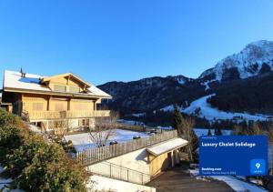 a large house with a snow covered mountain at Luxury Chalet Solidage in Rougemont