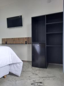 1 dormitorio con nevera negra y TV en Pousada & Hotel Fazenda Segredo Das Águas en Alto Caparao