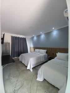 2 camas en una habitación de hotel con sábanas blancas en Pousada & Hotel Fazenda Segredo Das Águas en Alto Caparao