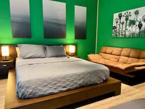 a bedroom with green walls and a bed and a couch at The Tatman Evergreen Suite in Lake Alfred