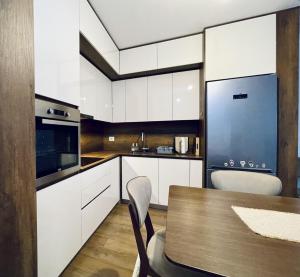 a kitchen with white cabinets and a wooden table at Apartment with balcony in Gjakove