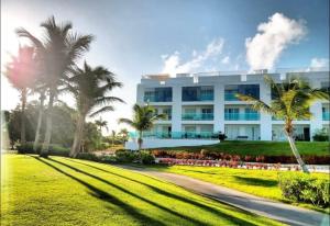 un gran edificio blanco con palmeras delante en New Casino, beach and golf condo at Hard Rock Punta Cana area en Punta Cana