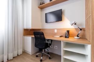 a desk with a chair and a television on a wall at Canal do Anfitrião | Studios delicinhas in Sao Paulo