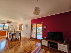 a living room with a red wall and a table with chairs at Apartman More in Lun