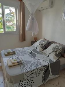 - un lit avec une couette en noir et blanc et une fenêtre dans l'établissement F2 proche plage Anse Mitan, à Les Trois-Îlets