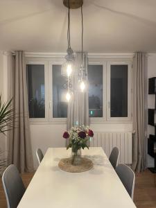 a dining room with a table with a vase of flowers at Appartement Cosy Beauvais in Beauvais