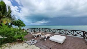 2 sillas y terraza de madera con vistas al océano en On The Beach - Seaside Sunset Haven en Cancún