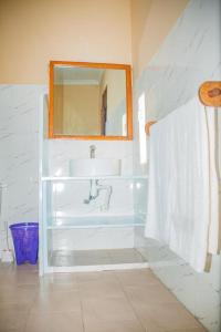 a white bathroom with a sink and a mirror at Mafia Neptune Villa Lodge in Utende